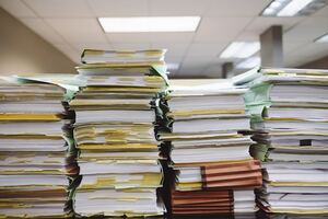 Photographie de plusieurs dossiers qui s'accumulent sur un bureau